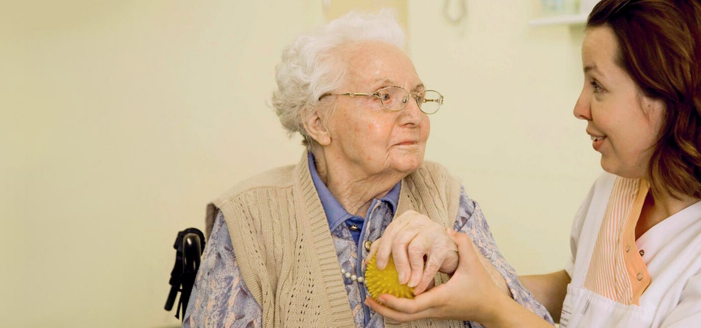Pflegerun hält Hand einer Seniorin