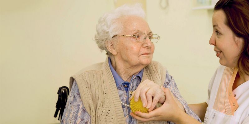 Pflegerun hält Hand einer Seniorin